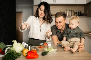 Familia cocinando juntos (padre, madre y niño con alimentos saludables).