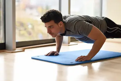Persona haciendo flexiones y fondos en el salón.