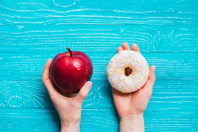 Manos sosteniendo un tazón de frutas vs. dulces.